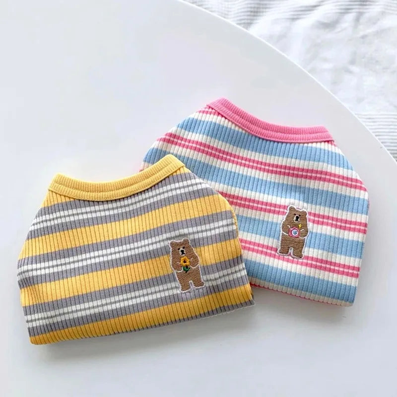 Two striped pet sweaters with bear designs on a white surface