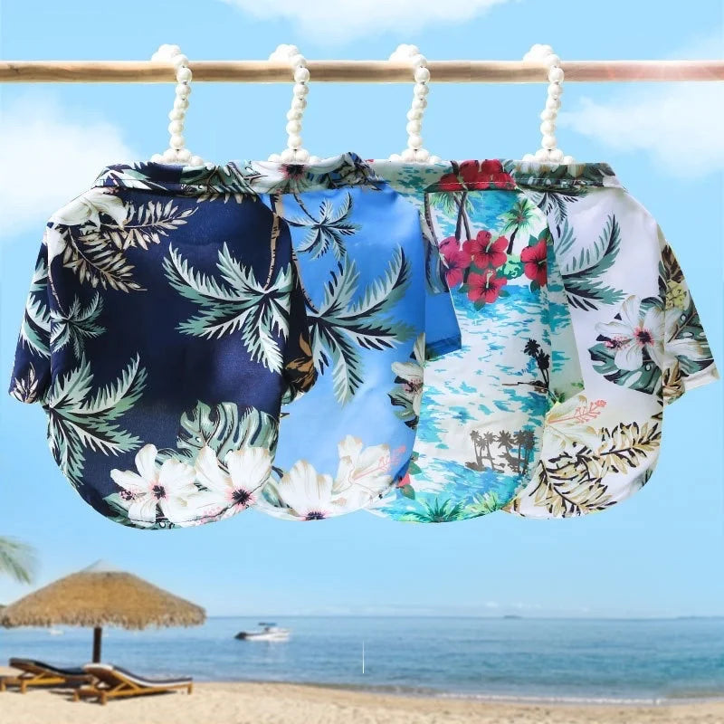 Hawaiian shirts with floral patterns hanging on a clothesline against a beach backdrop.