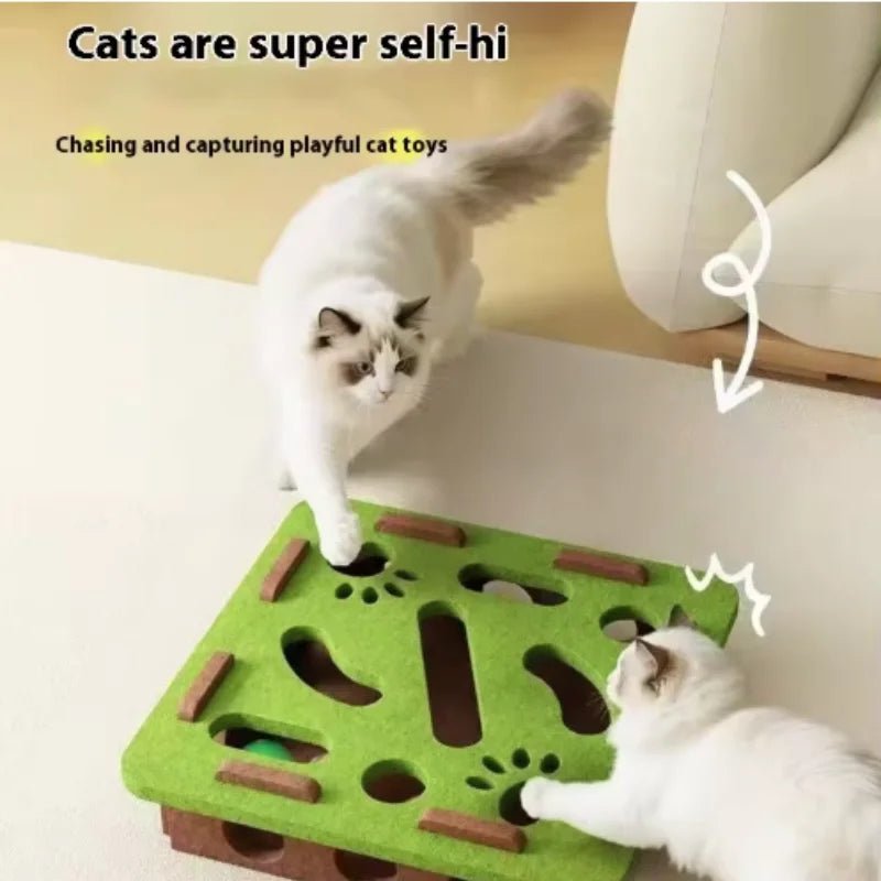 Two cats playing with a green cat toy on a beige couch.