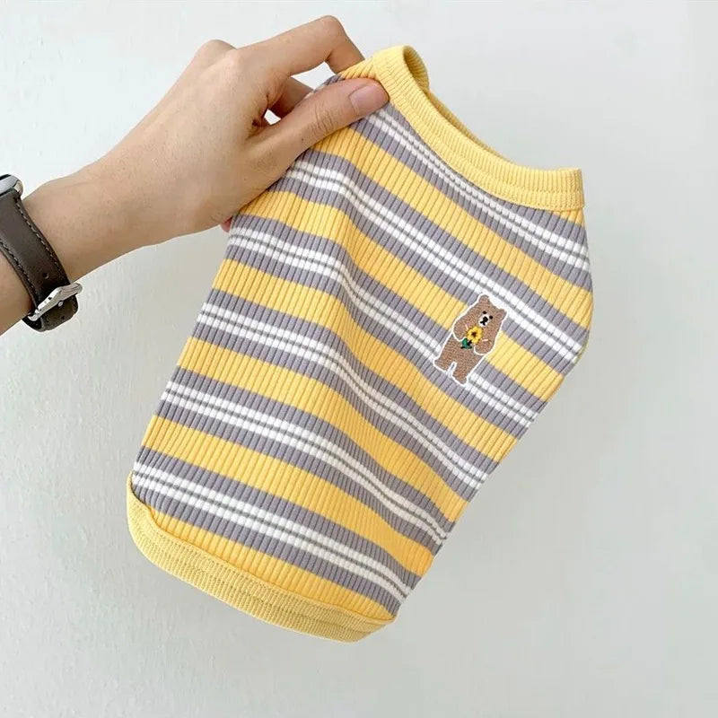 Yellow and gray striped pet shirt with a bear design held by a hand on a light background
