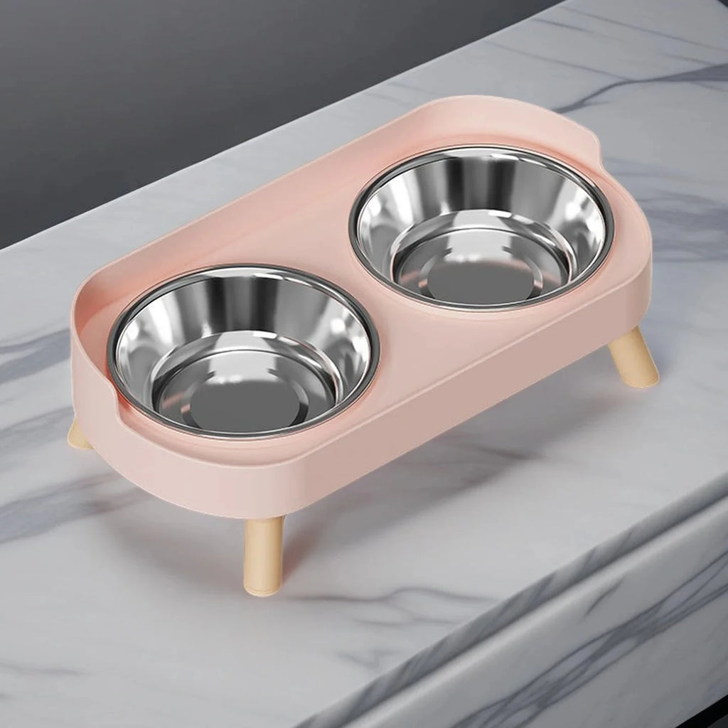 Pink pet feeder with two stainless steel bowls on a marble surface