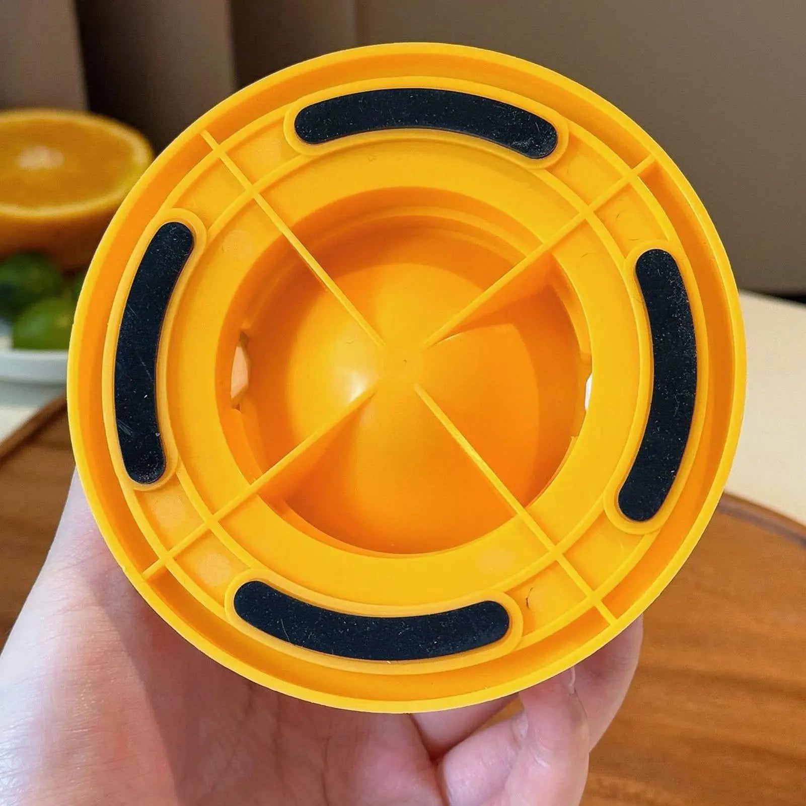Yellow plastic lid with black straps held in a hand on a wooden surface.