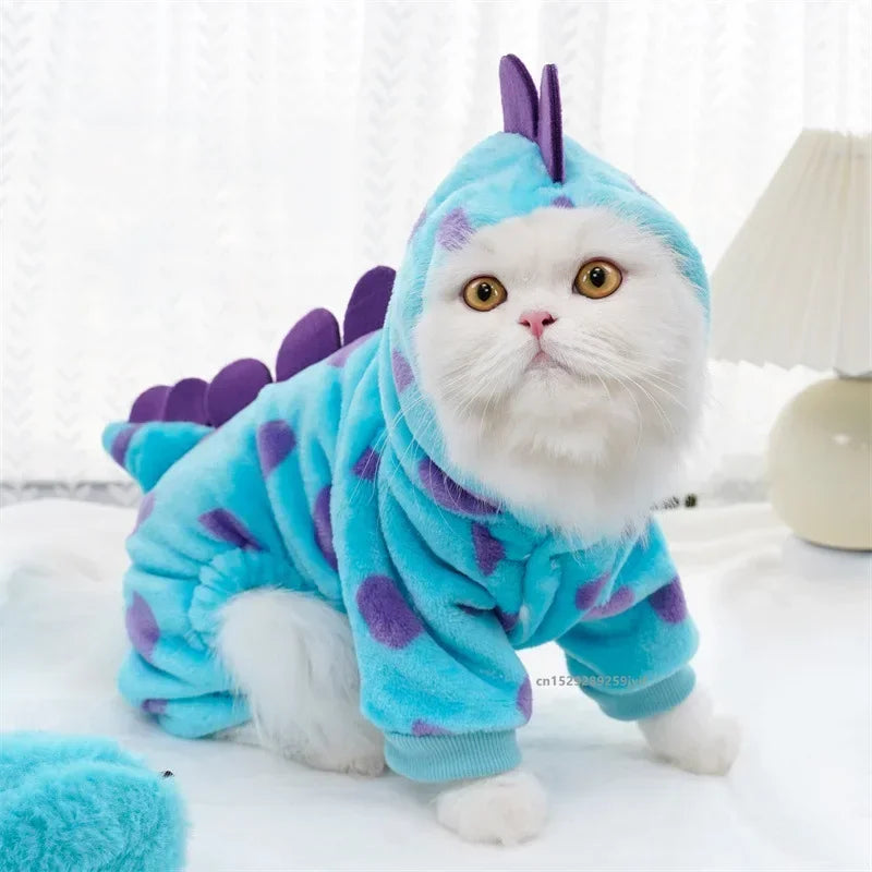 Cat wearing a blue dinosaur costume with purple spikes on a white background