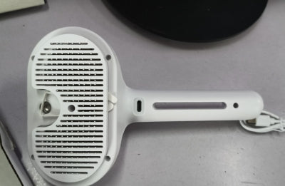 White handheld electronic device with a grid-like surface on a gray background