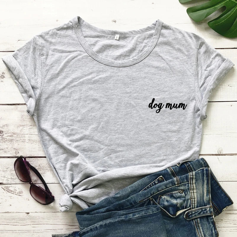 Gray t-shirt with 'dog mum' text, sunglasses, and jeans on a wooden surface
