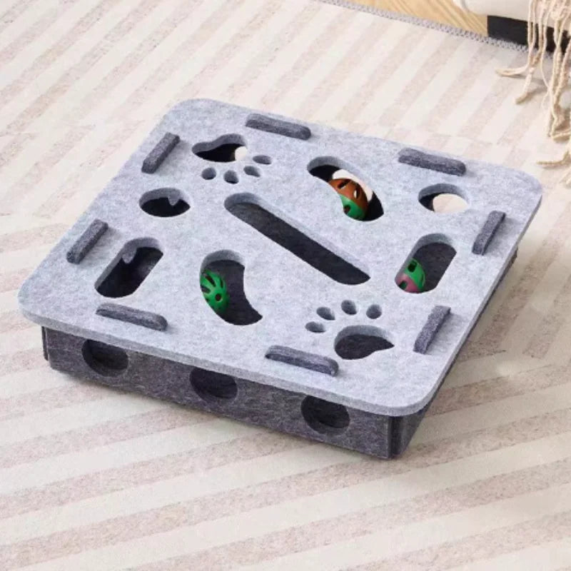 Gray pet play structure with multiple holes and a green toy on a light wooden floor.