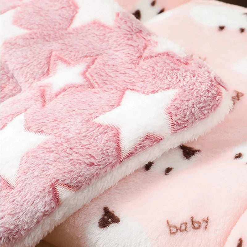 Close-up of a pink and white blanket with star patterns and the word 'baby' on a soft background.
