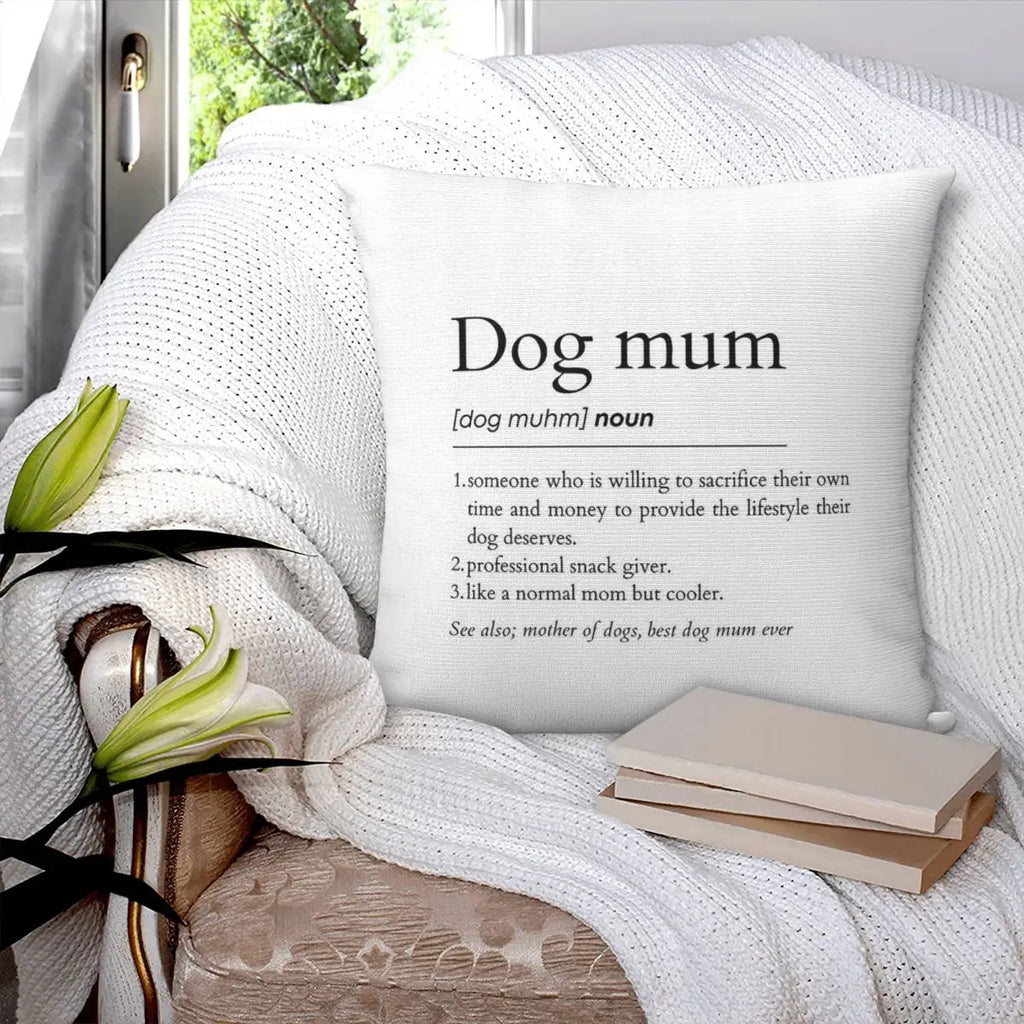 Decorative pillow with 'Dog mum' definition on a white surface with flowers and books.