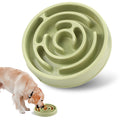 Green maze-style dog bowl with a dog eating from it on a white background