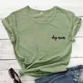 Green t-shirt with 'dog mum' text on a wooden surface with jeans and sunglasses.