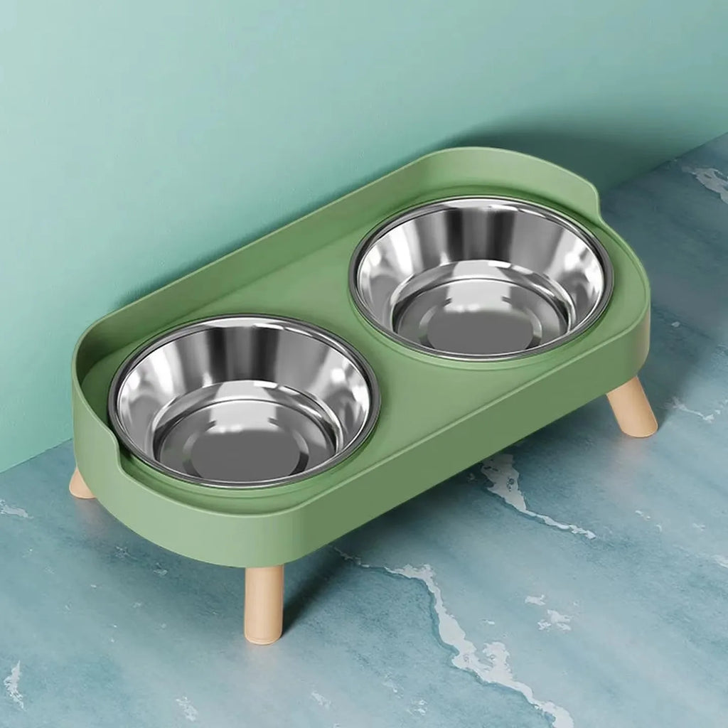 Green pet feeder with two stainless steel bowls on a blue surface.