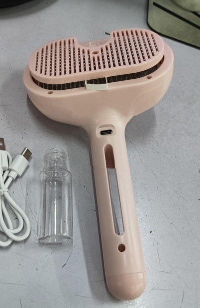 Pink handheld device with USB cable and clear bottle on a gray surface