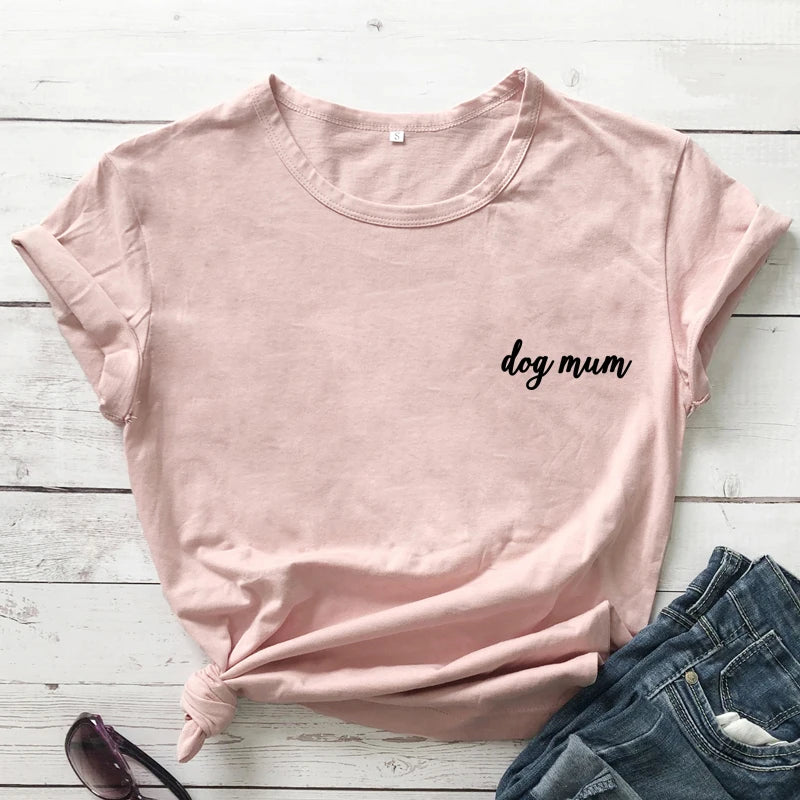 Pink t-shirt with 'dog mum' text on a wooden surface with jeans and sunglasses.